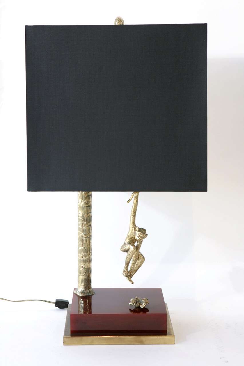 A whimsical pair of brass and resin monkey table lamps with custom black silk shades. A monkey appears to hang from the palm tree stem of the lamp and there's a decorative finial atop the shade. The lamps have an in line switch on the cord.