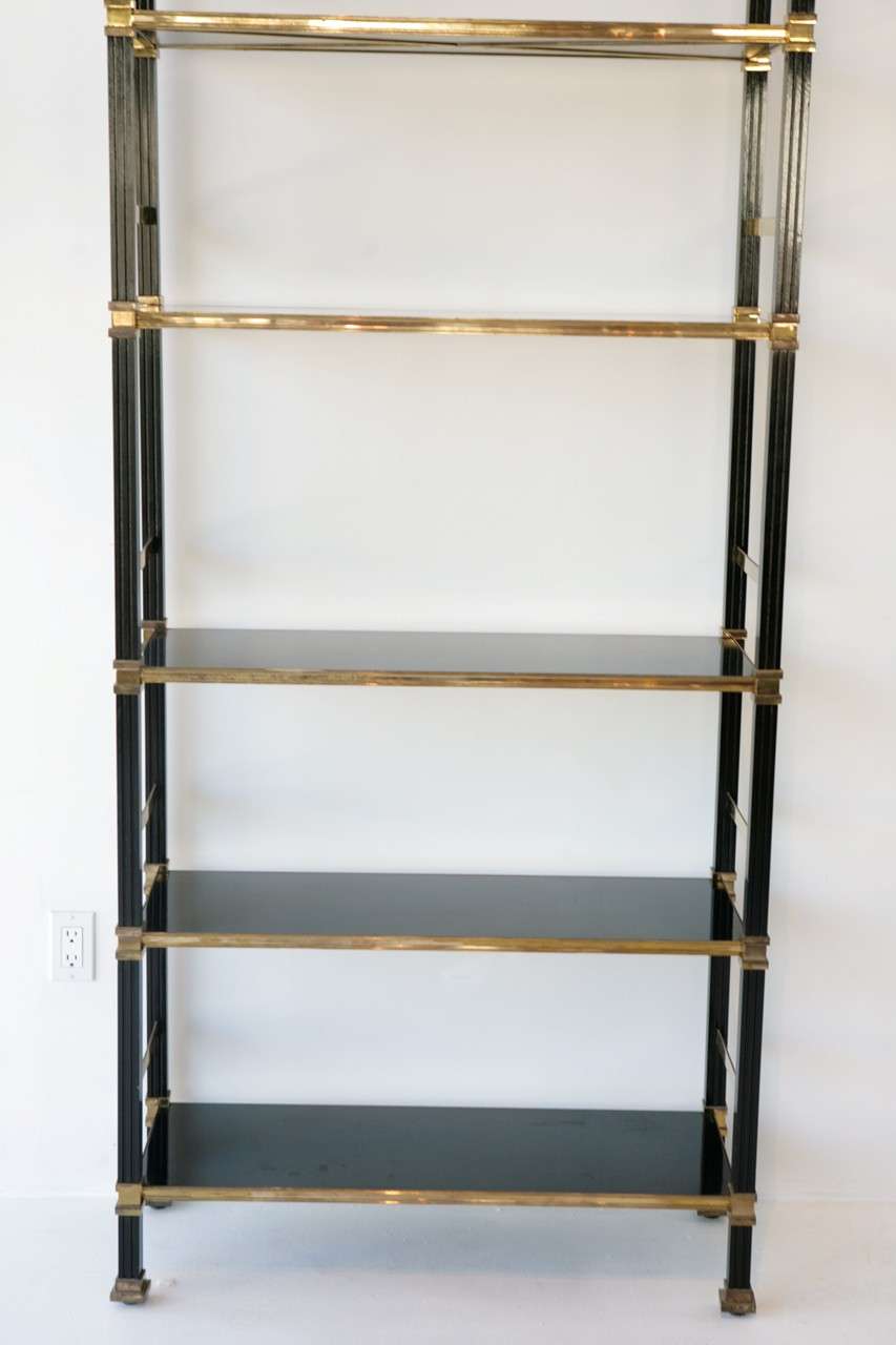 These dramatically scaled Regency style brass and black lacquer bookshelves feature an X design on the underside of each shelf. The top shelf has hardware to attach the bookshelves to the wall and the feet have levelers. We have five bookshelves in