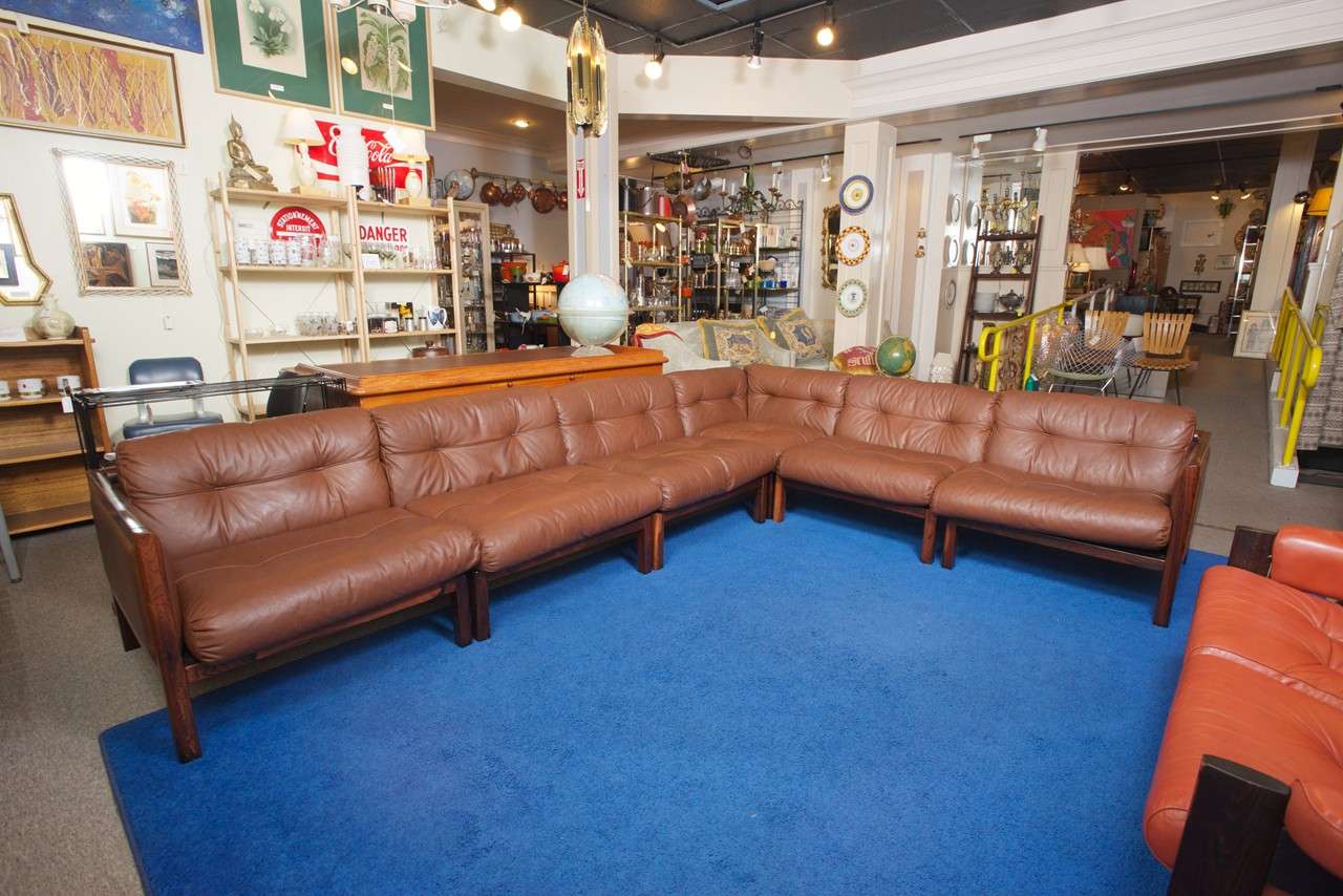 This monumental (circa 1970's) Danish modern modular sofa, has a rosewood frame and rich chocolate colored down over foam leather cushions. The versatile modular design has six sections, all with leather backs. The end sections have a high tuxedo