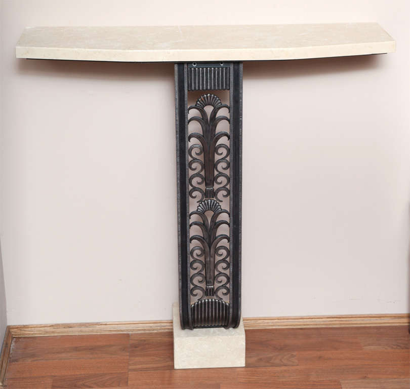 Art Deco style console in the manner of Edgar Brandt.

Wrought iron, with travertine top and base.

Measures: Height 37 1/2 in, length 37 1/2