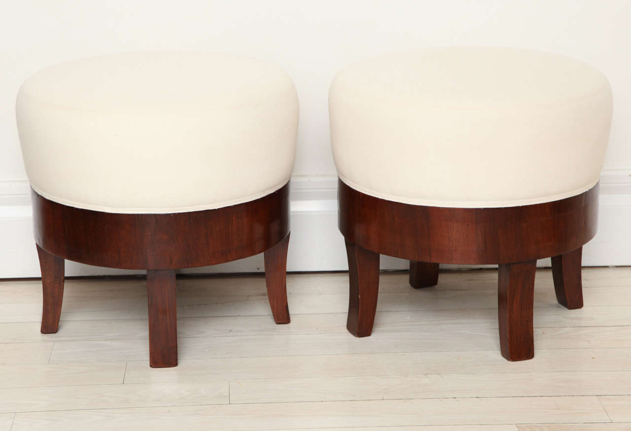 Pair of round walnut poufs with slightly flared legs and upholstered seats