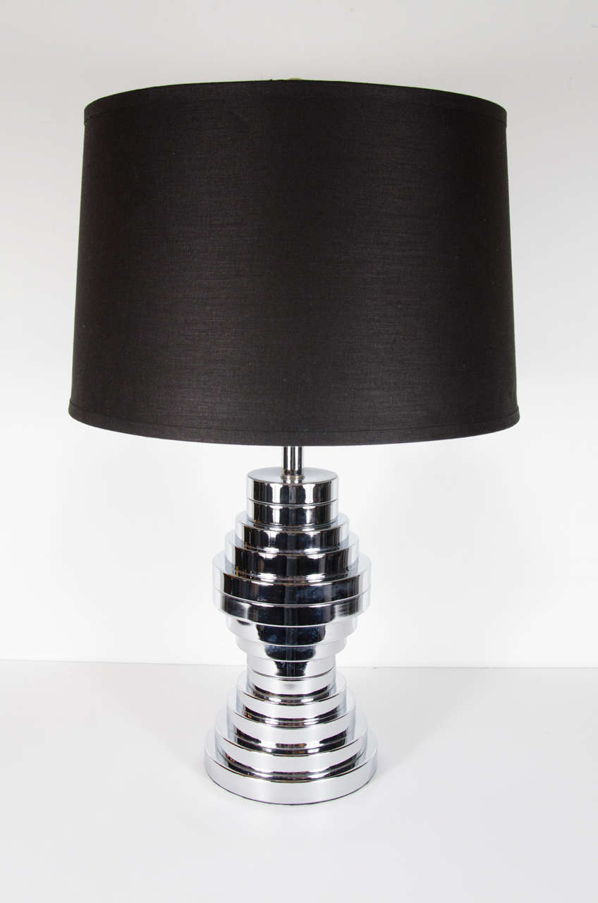 This refined Modern lamp features a skyscraper style design consisting of multiple chrome tiers in an abstracted hour glass form. The stepped design represents an ode to Art Deco, but with a distinctly Mid Century Modern sensibility. With its