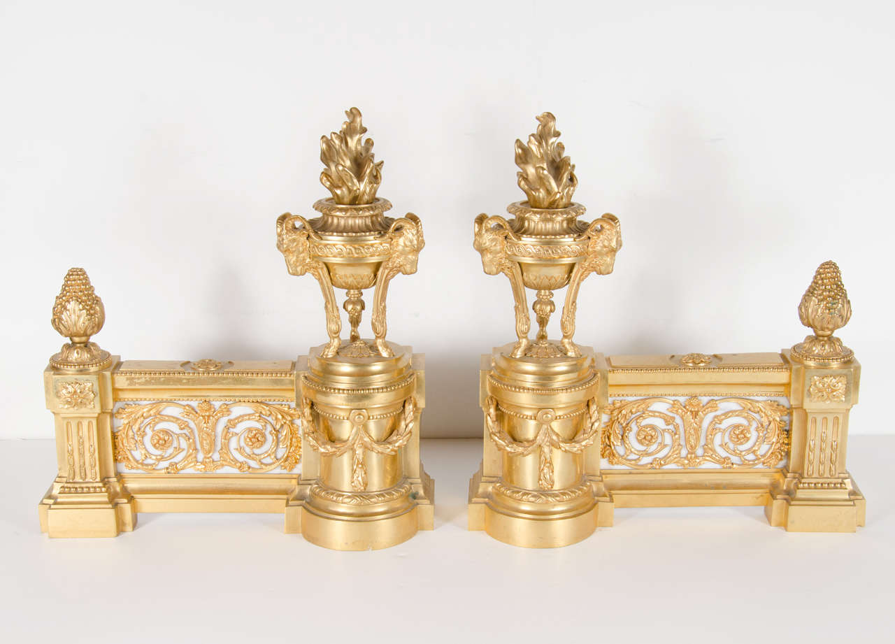 A fine pair of antique French Louis XVI style doré bronze chenets or andirons of exquisite workmanship embellished with neoclassical urns adorned with flames and mythological satyrs representing fire in original doré bronze mercury gilding, they are