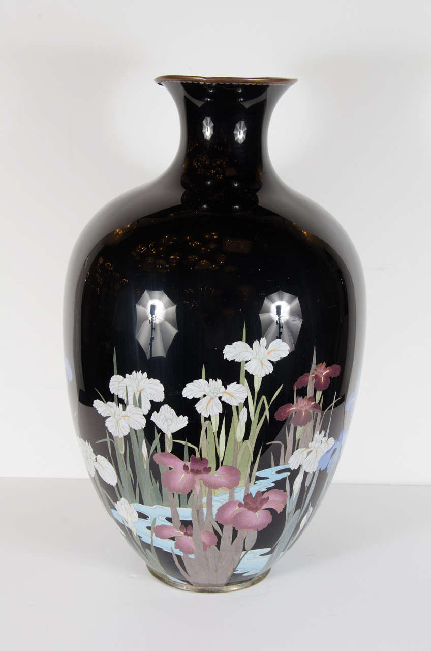 This large scale vase features a black enameled background with handpainted renditions of white, mauve and royal blue floating in a pond. The base of the piece as well as the inside of the rim have been lined in antique brass. It would be perfect