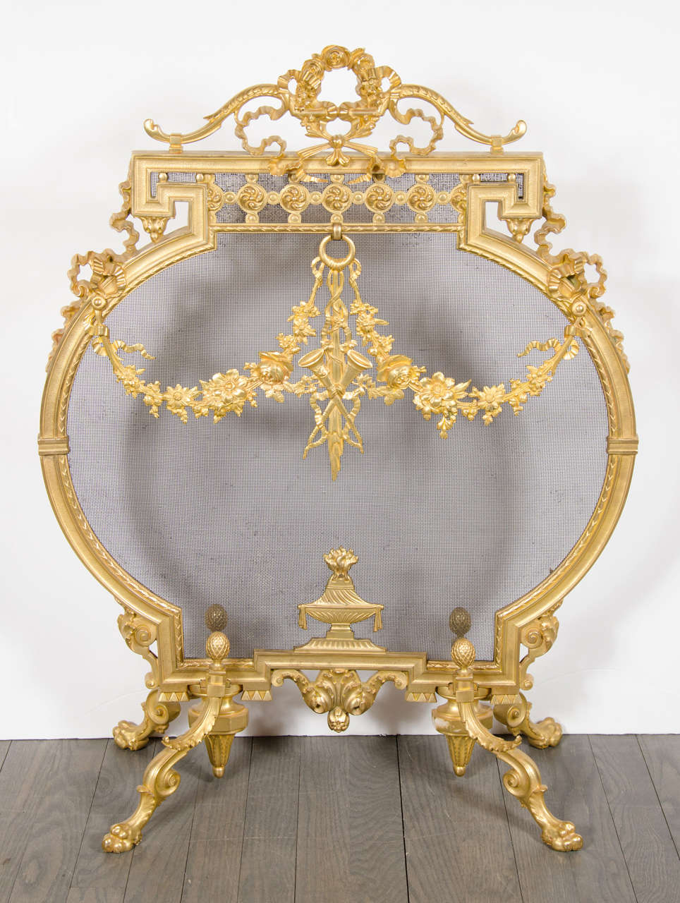 This magnificent fire place cover/screen is made of Dore Bronze and features motifs of garland,wreaths with stylized Greek key detailing .It also has details of a bow,lute and horn all supported by claw feet.This is truly an exquisite piece in