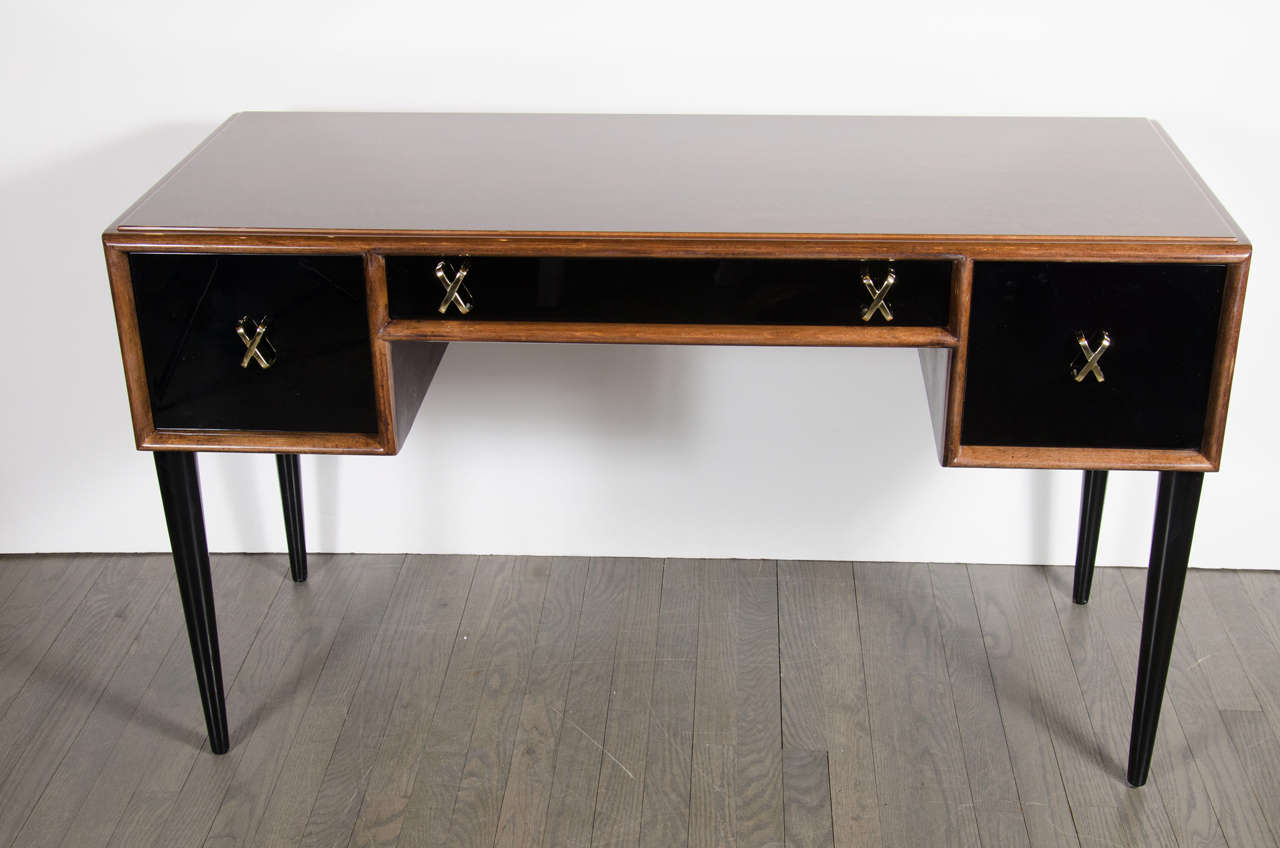 This desk / Vanity designed by Paul Frankl for Johnson furniture co of Grand Rapids is made of book-matched walnut with ebonized drawers and conical shaped legs. The Drawers also feature polished brass x form pulls. This piece has been mint restored.