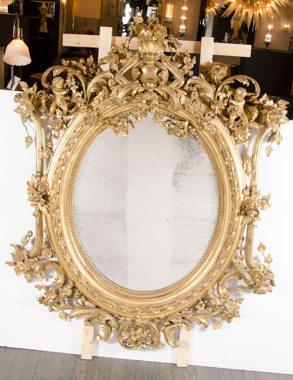 Magnificent 19th Century French Rococo oval mirror with 24K gold gilt details and stylized foliage detailing.  This stunning 19th Century French Rococo mirror is a true work of art with its hand-carved detailed surround that features a top crown of