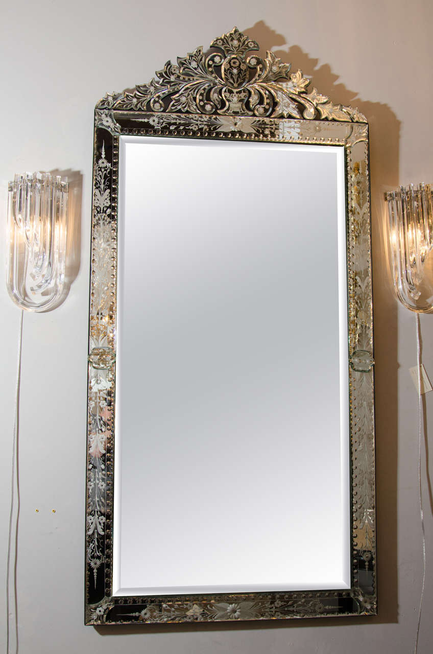 This beautiful 1940's Hollywood Venetian mirror features elaborate reverse etched floral & convex detailing with chain beveling and appliqué detailing on the corners and mid-point. It has a majestic cartouche that really gives this mirror presence.