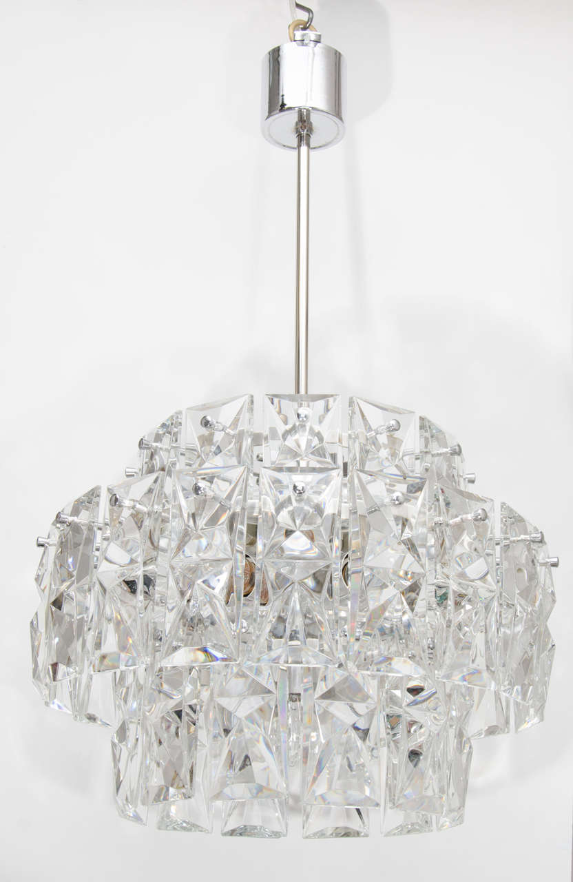 This sophisticated chandelier features three tiers of faceted cut-glass crystal prisms. The frame of the chandelier is polished nickel. It has been completely rewired and the height can be adjusted to suit. The height of just the glass is 14.