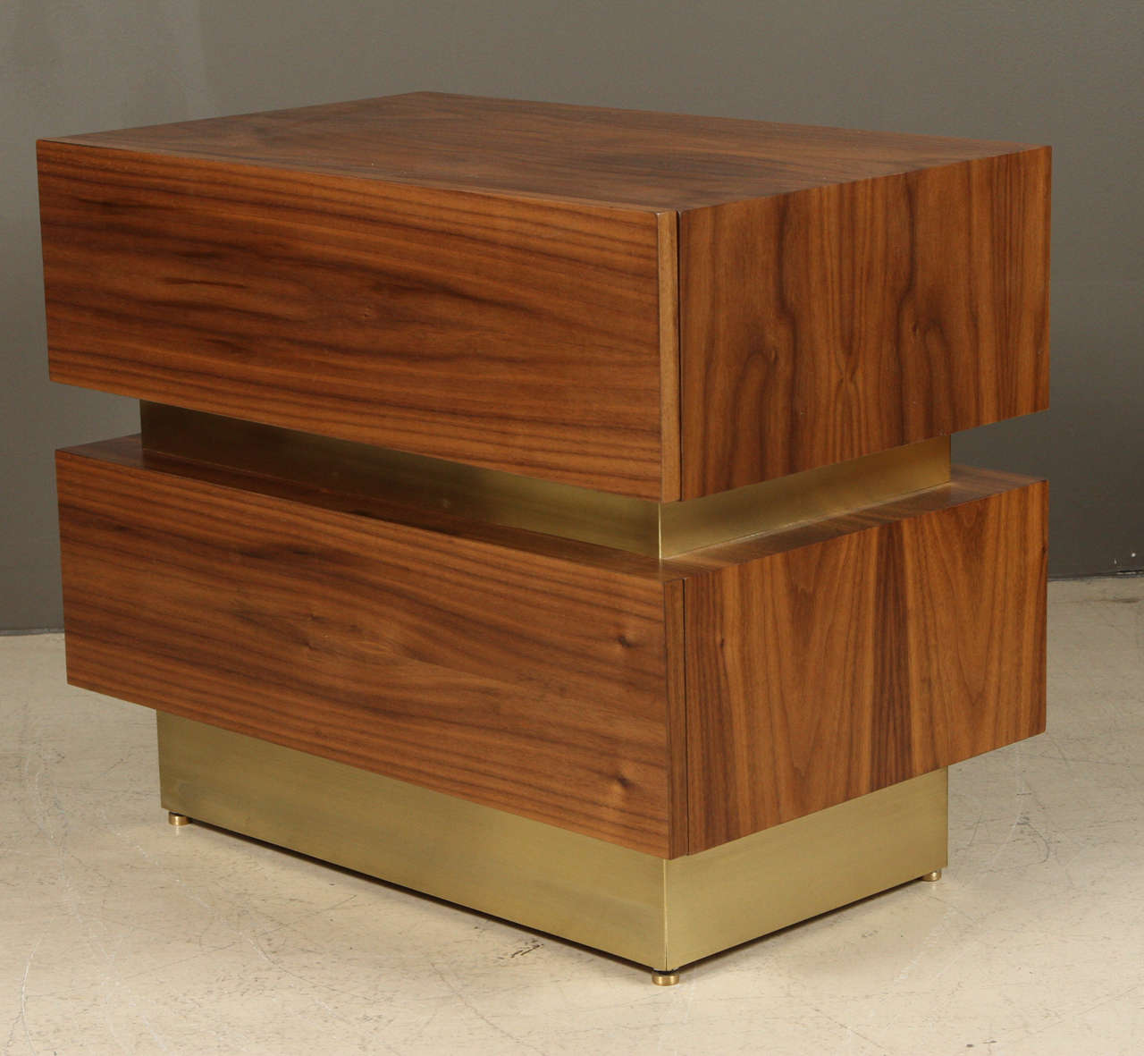 The stacked box nightstand is a two drawer bedside table. This pair is done in brass a light walnut.