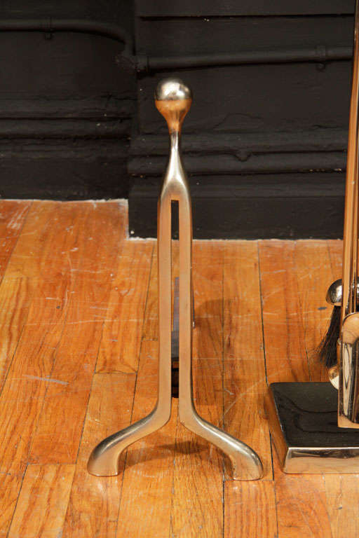 Set of sleek, modern nickeled bronze fire tools and andirons. In addition to the two andirons and the fire tool stand, the tool set consists of a broom, spade, poker and tongs.<br />
Andiron Dimensions: 18