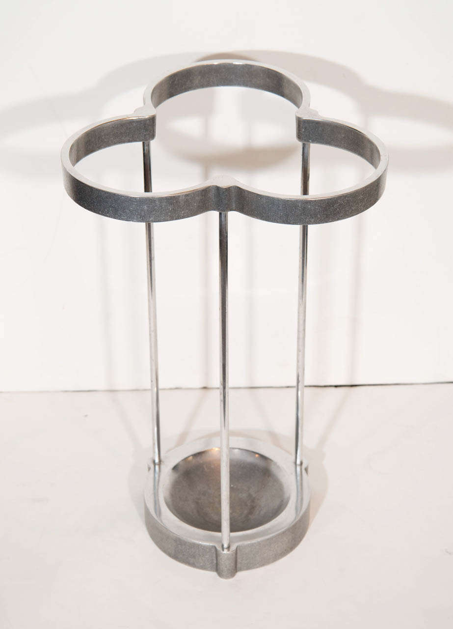 Cast aluminum umbrella stand with pewter finish has modernist design with stylized ivy or trefoil top, triple stem details, and circular concave base.  Holds up to nine umbrellas.