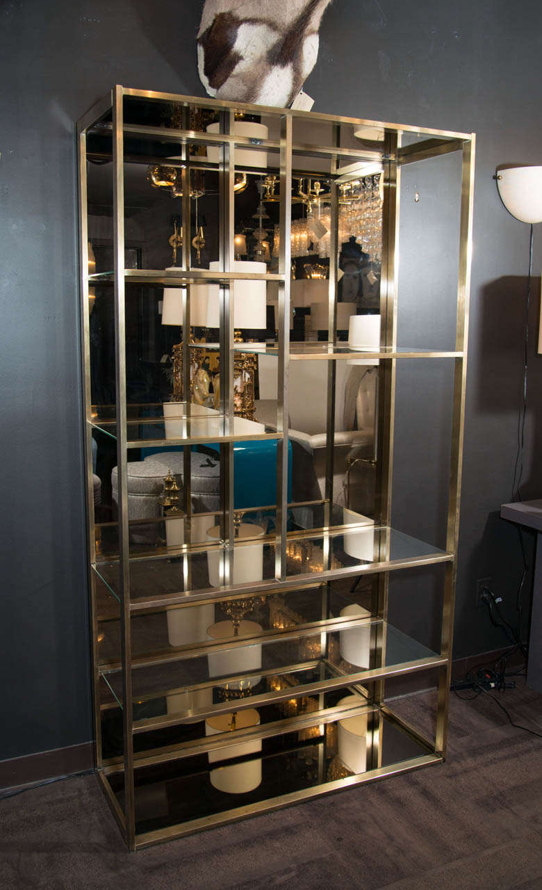 Exceptional multi-tiered étagerè or book case display with asymmetrical tiers. 
The étagerè has a streamline patinated brass frame with bronze mirrored backing as well as bronze mirrored top glass and bronze mirrored lower shelf glass. The