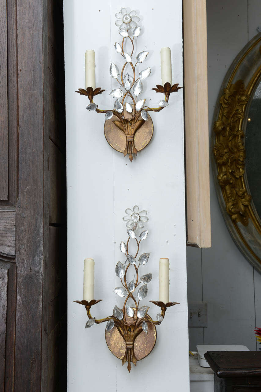 2 light sconces mounted on backplate with crystal leaves on arms extending up an twined vine to a single flower