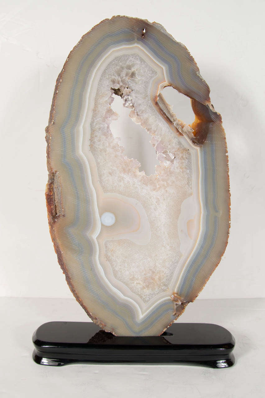 This gorgeous sliced crystal geode specimen has a central opening lined with thousands of crystals that catch the light beautifully, surrounded by numerous rings of pearlescent hues of gray's, pale blue's, amber's & white.  It has a perfectly,