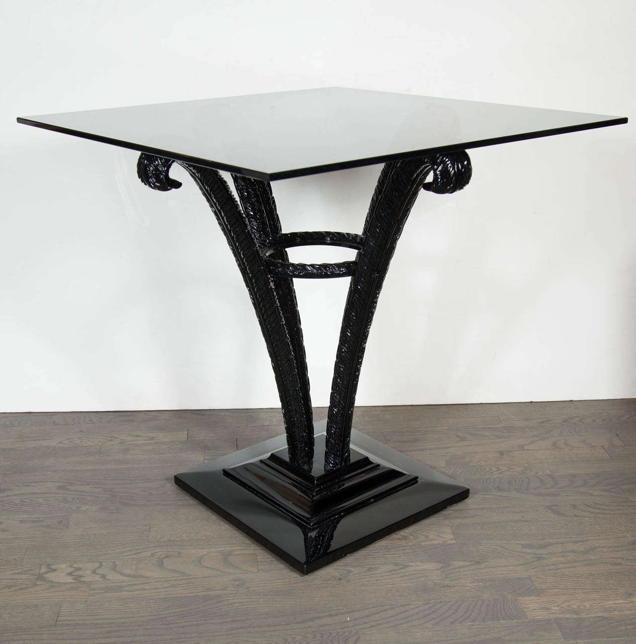 This elegant Art Deco occasional table was realized by esteemed maker Grosfeld House, where legendary designers such as Lorin Jackson got their start, circa 1930. It features four stylized ebonized walnut plumes supporting a square smoked glass