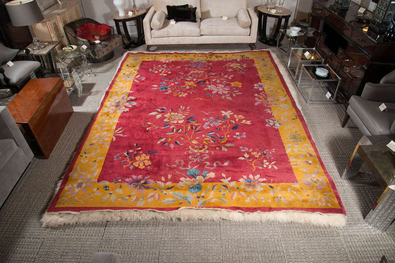 Chinese Art Deco 9 x 12 rug featuring a light, beautiful floral pattern with stylized foliage design in hues of pale and rich blues, teals, plums, light and dark ambers, amethyst and hues of greens.  It has a center and outside trim of ruby red