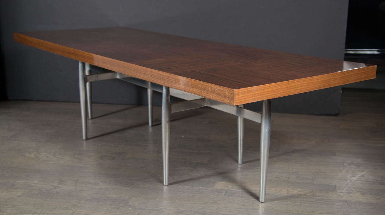 A stunning Mid-Century Modern cocktail Table by Donald Deskey for Charak Furniture Co. featuring book matched walnut panels in contrasting grain direction atop a streamlined brushed aluminum sculptural base. Restored to mint condition.