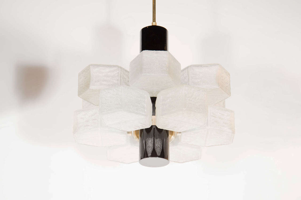 This mid-century chandelier has a unique design using 12 textured glass hexagonal globes that emanate from it's center giving it a honeycomb effect. It also features ebonized walnut and antique brass fittings.Its been completely rewired and the