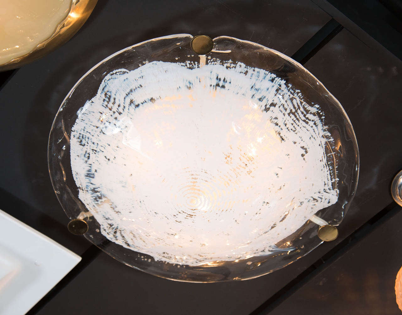 A Mid-Century Modernist dome shaped flush mount by Mazzega in clear high quality hand blown glass with a white semi-transparent textured central design. The thick glass has an organic quality to it which is secured with brass fittings. It has been