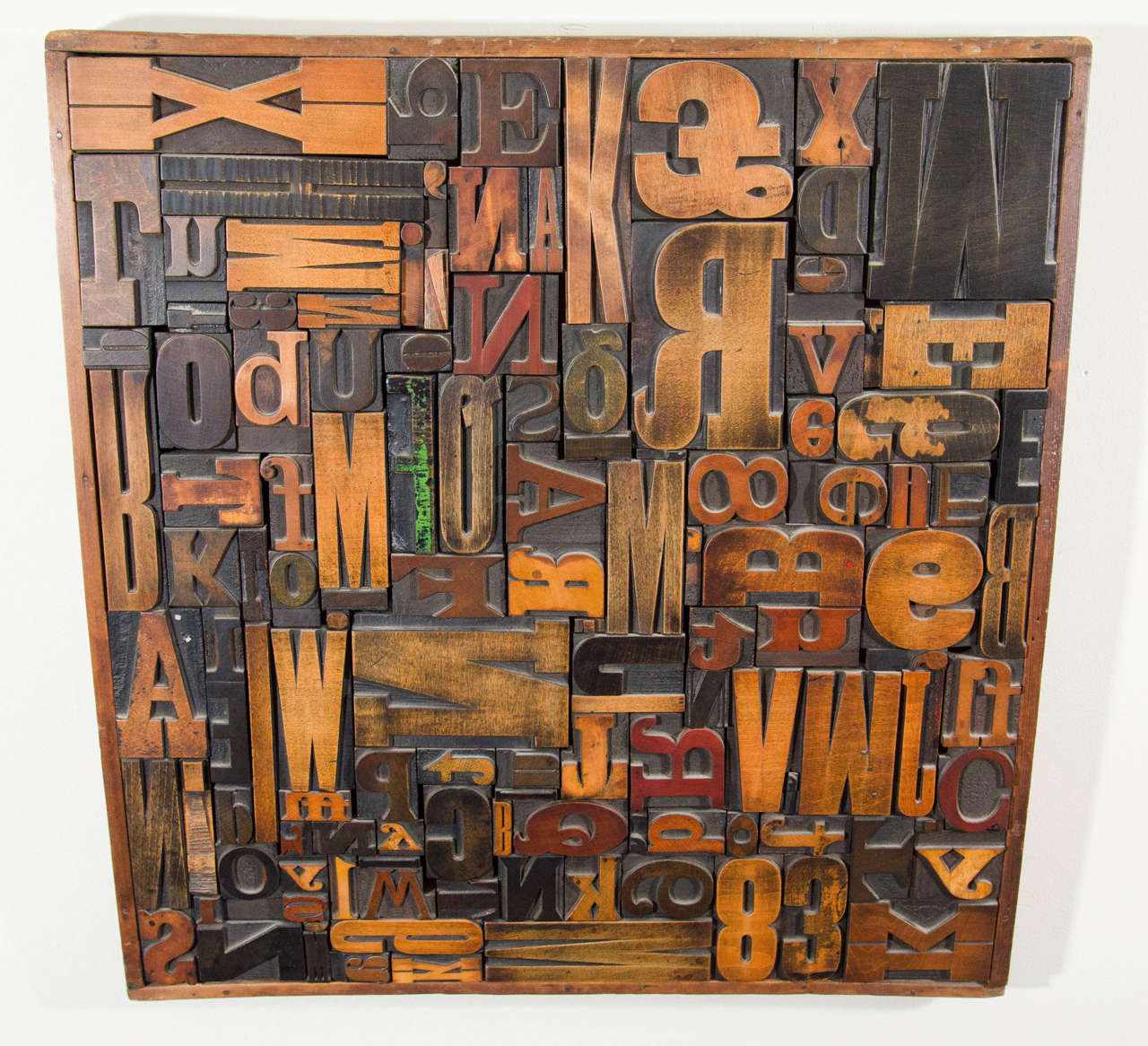 A vintage letterpress printers blocks wall sculpture with a variety of letters and numbers in a wooden frame.  Good vintage condition with age appropriate wear.  One letter is green.  There is a second letterpress printers blocks wall sculpture