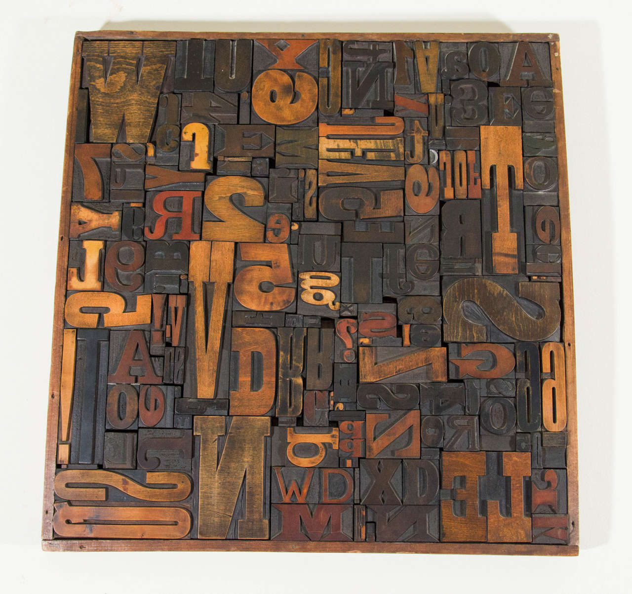 A vintage wall sculpture composed of letterpress printing blocks, produced circa 1960's - 1970's, with a variety of letters and numbers in a wooden frame. Good vintage condition with age appropriate wear. 

Second letterpress printing blocks wall