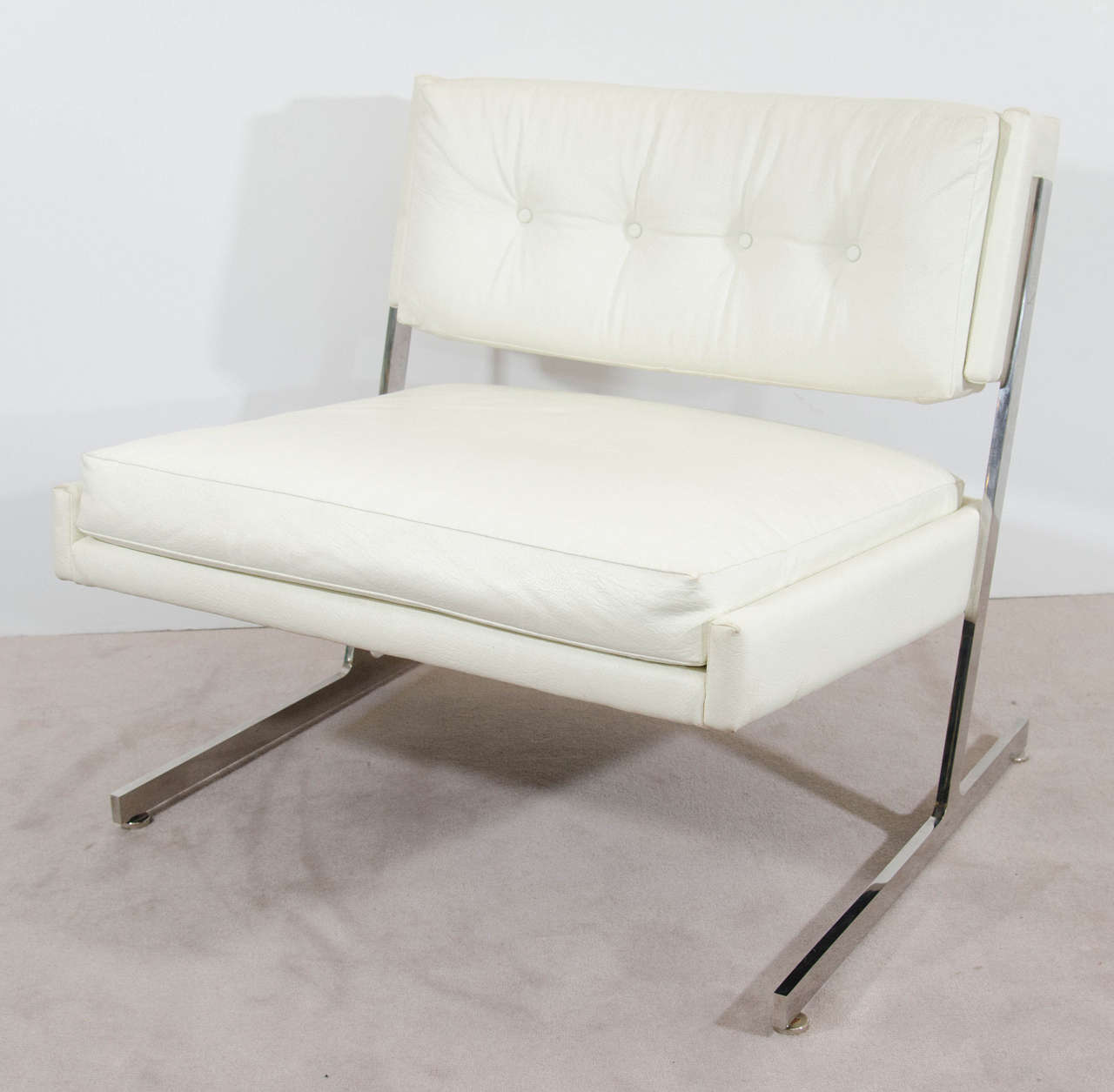 A vintage pair of white button tufted faux leather and chrome Harvey Probber lounge chairs.