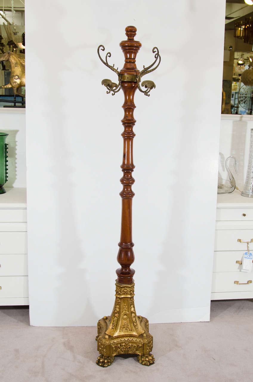 A 19th century wooden coat rack with eight hooks, and an ornately carved gold painted wooden base with paw feet.