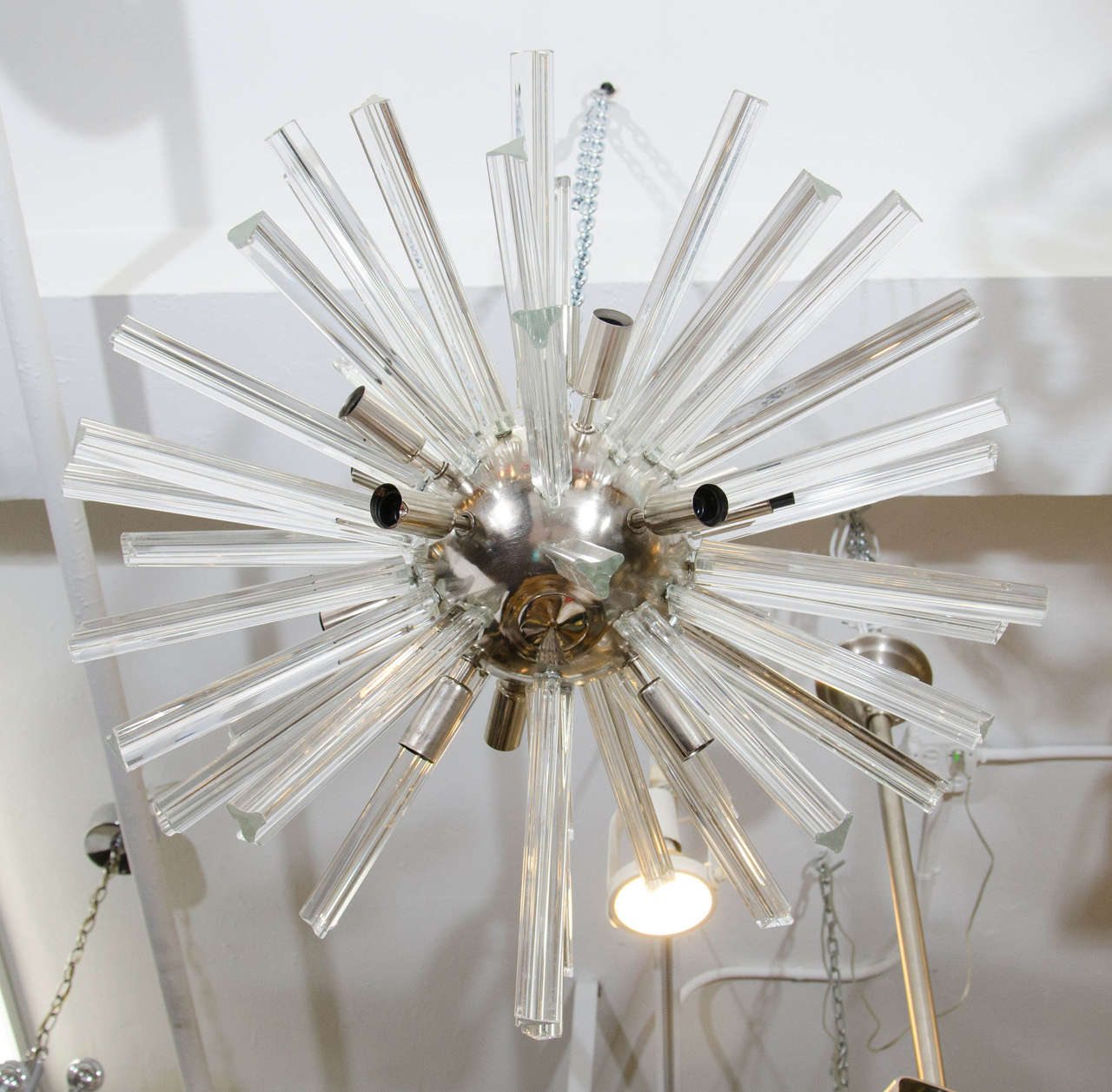 A vintage Sputnik chandelier with clear glass rods radiating out of a chrome spherical center. Good vintage condition with age appropriate wear. Several sockets are bent or need adjustment and there are a few crystals with chips and scratches.