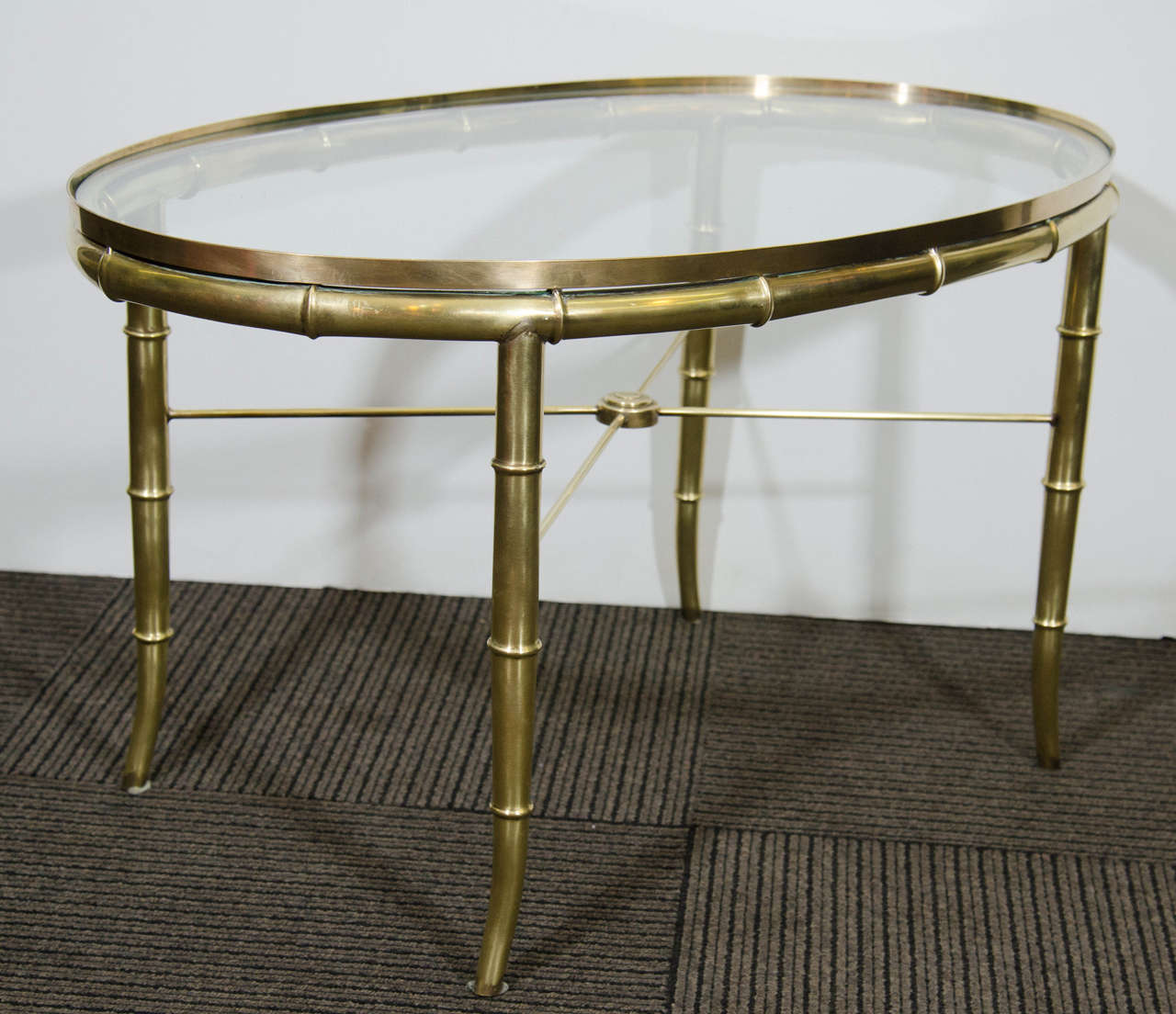 A vintage oval brass and glass tea table/occasional table by Mastercraft with Faux bamboo Motif.

Good vintage condition with age appropriate patina.