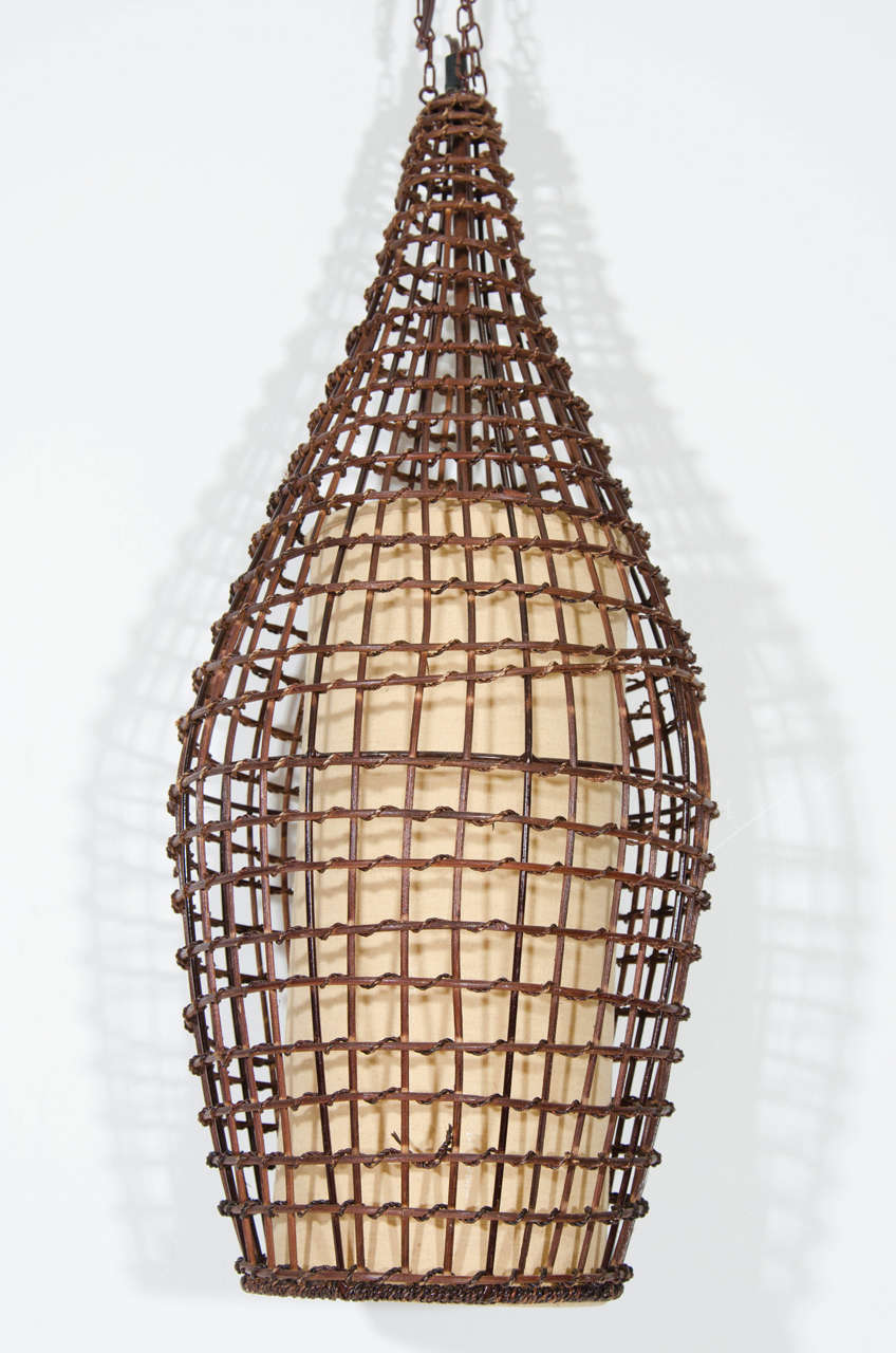 A vintage basket style wicker pendant or lantern in dark off-black with cream colored canvas shade interior, circa 1970s. Good vintage condition with age appropriate wear. May need rewiring.