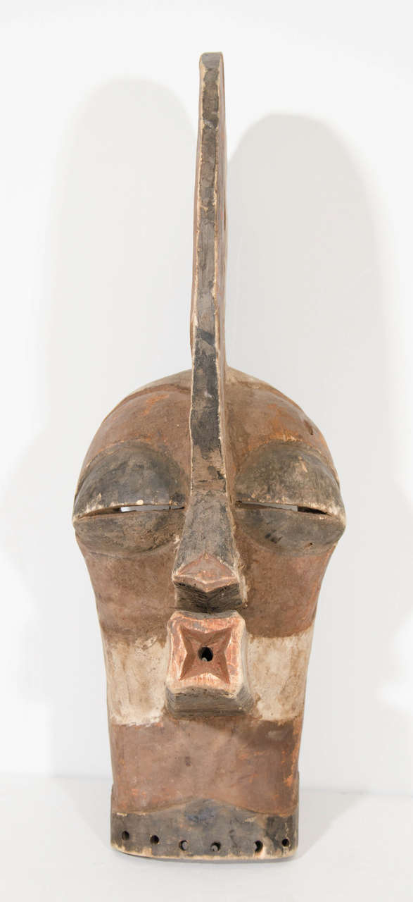 A large carved wooden mask, decorated with red, white and black pigments, in the style of a ceremonial kifwebe, of the Songye People, a Bantu ethnic group from the central Democratic Republic of Congo. Similar to the traditional kifwebe masks, the