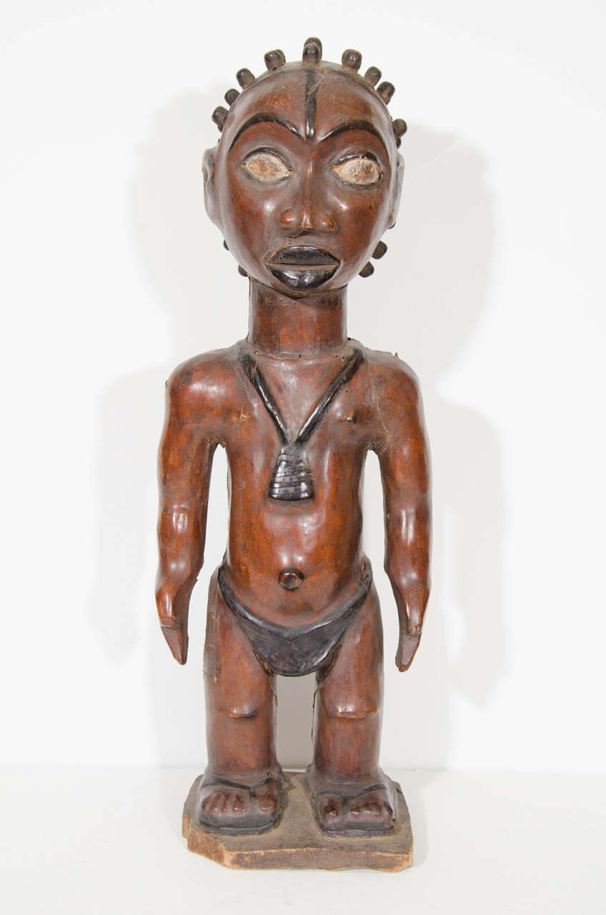 A pair of male and female statues, produced circa 1950s, inspired by the traditional styles of the ethnic group Ekoi (or Ejagham) of southeast Nigeria and northern Cameroon. Both figures are based in wood, wrapped in leather with large eyes and