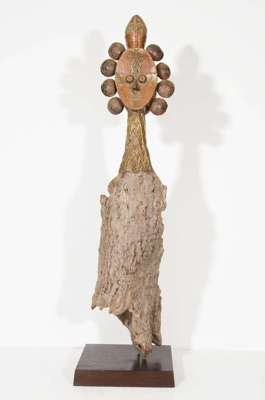 An early 20th century double-faced reliquary guardian figure in the style of Bakota (or Kota-Bantu ethnic group). The piece is constructed of copper and driftwood; decorated with an abstract headdress and mounted on a square wooden base. Used as a