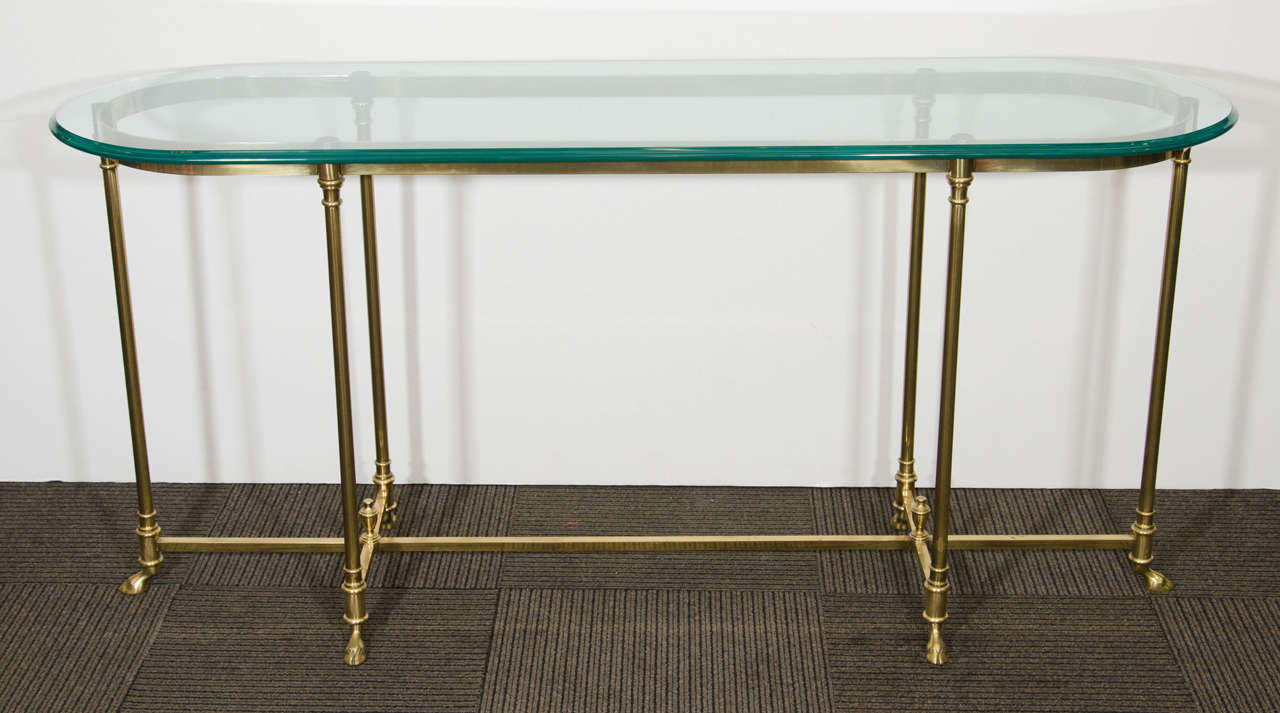 A Hollywood Regency style brass and glass console table with hoof feet by La Barge.  Good vintage condition with age appropriate wear and patina.   A few light scratches to the top.