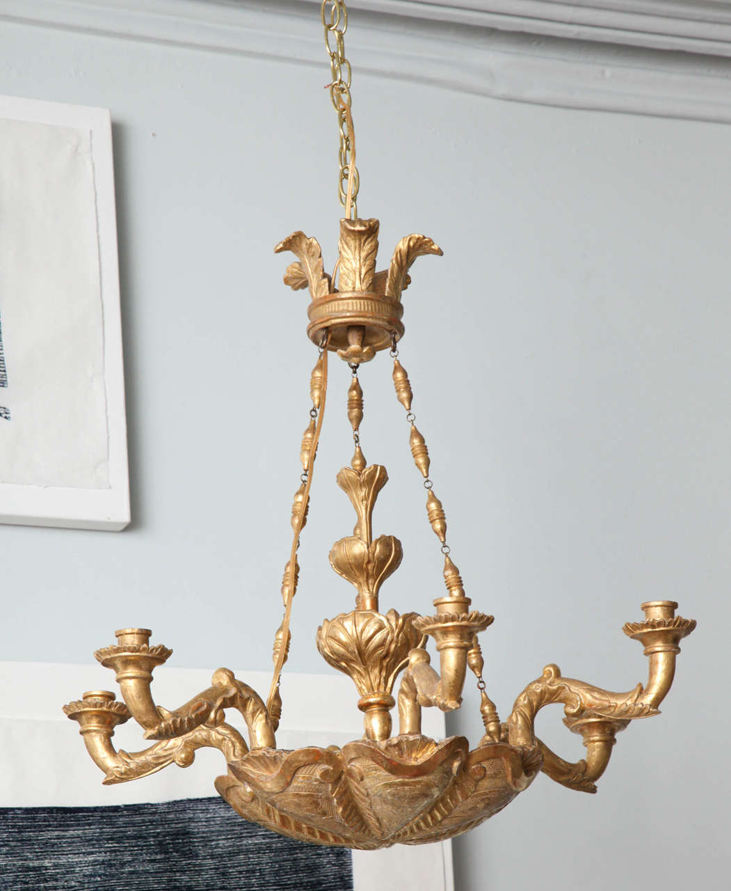 Early 19th century six lit giltwood chandelier, probably Vienna, circa 1830 having a feather carved cornice with three giltwood chains suspending a dished and loved body with scroll and leaf carving, the six arms with acanthus carving and scrolled