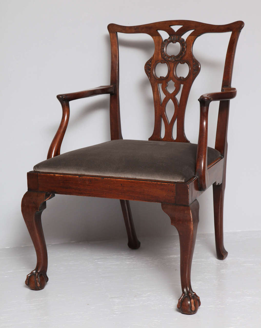 Rare set of four George II mahogany armchairs, the backs with pierced splats having carved foliate details, the arms with unique 