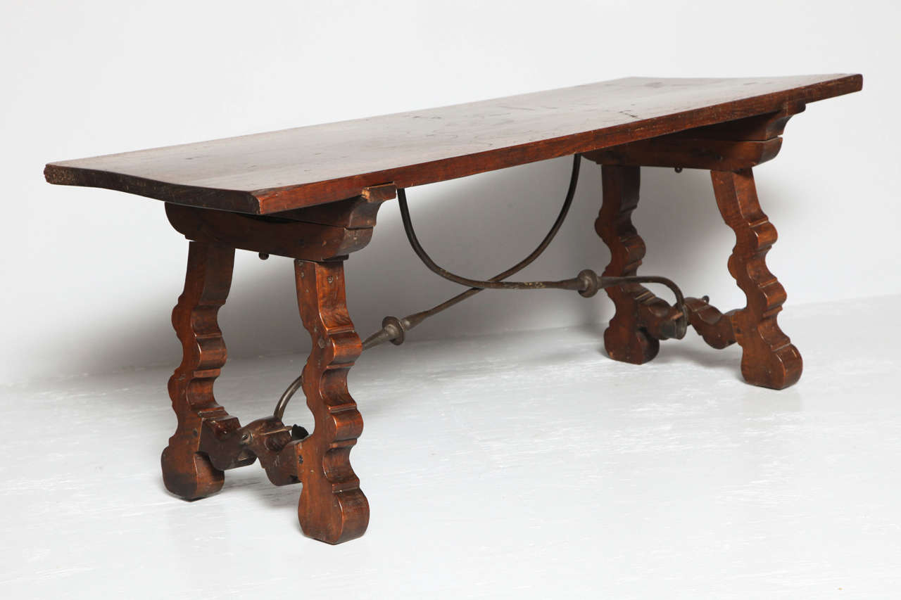 Very useful Spanish walnut Baroque period low table, the single plank top with rich color, over shaped trestle ends joined by original wrought iron stretchers, the whole nicely patinated and with rich surface.