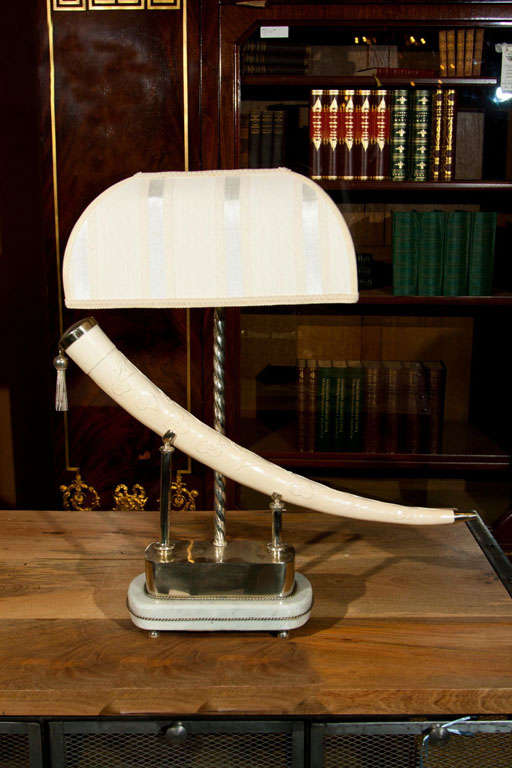 Hand-made table lamp; antique elephant tusk carved with flowers, tipped in silver with silver tassel. Mounted on think silver stands, on marble and silver base. Hand-woven fabric shade on twisted silver stand.
