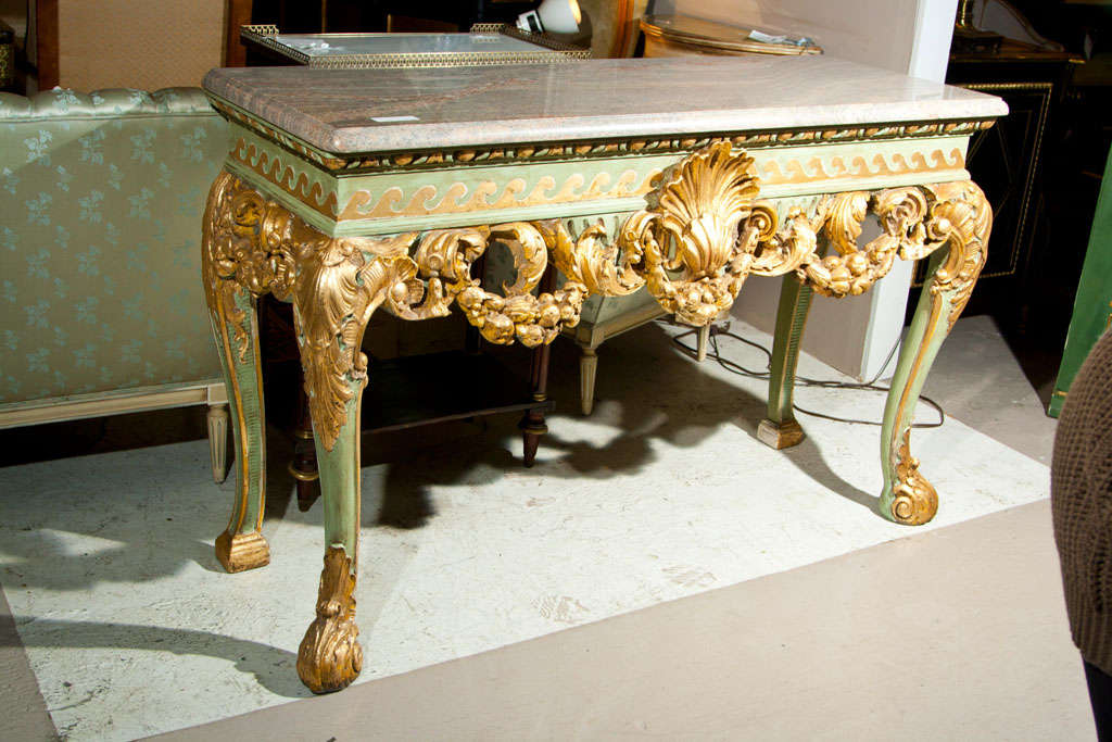French Rococo style console table, circa 1920s, the marble atop a green-painted and parcel-gilt base, with elegant decoration of carved foliate and shell crest. Bearing a label for Berkey and Gay Furniture Co