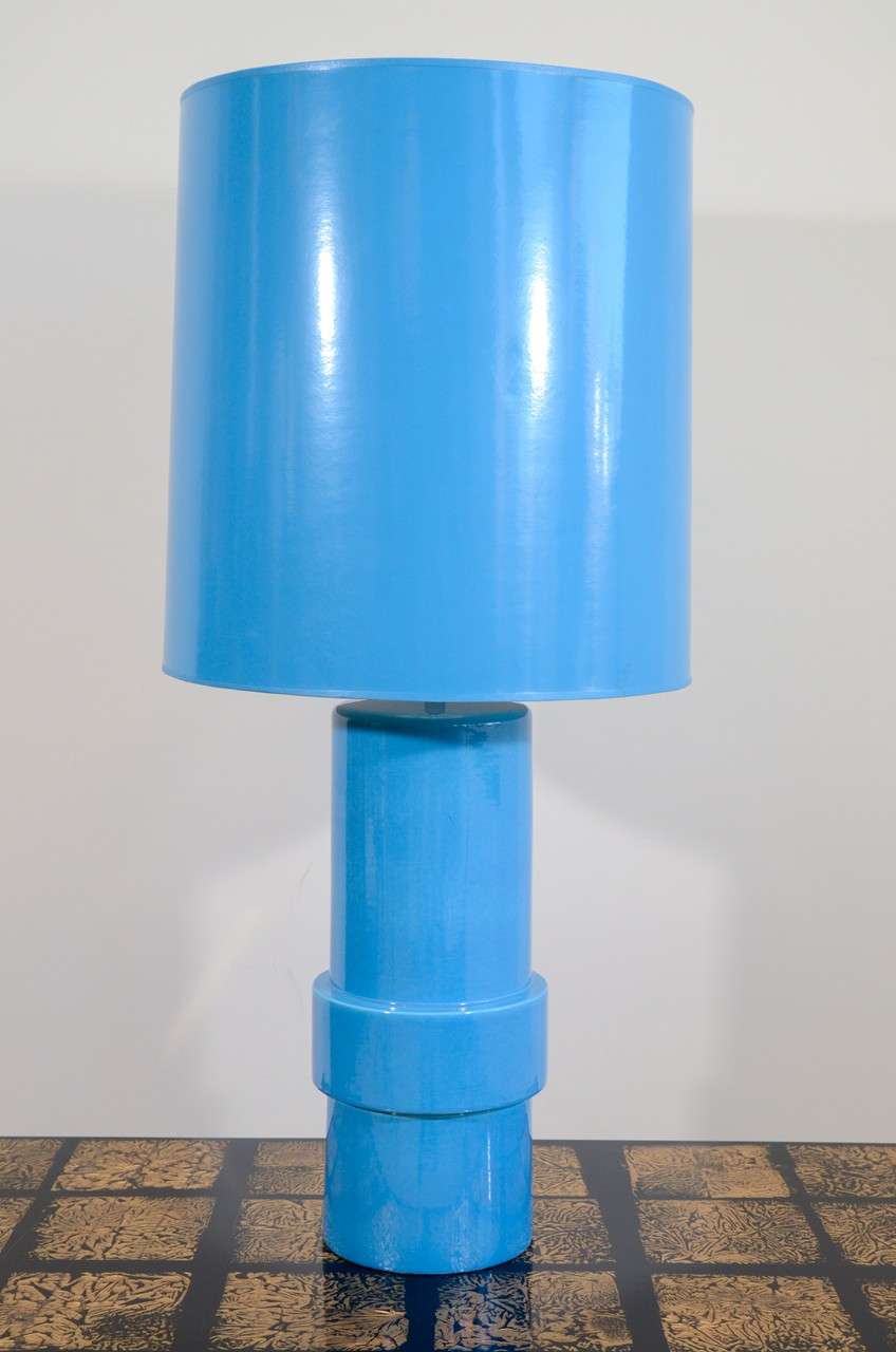 The slip cast ceramic cylindrical body with a raised band towards the base, covered with a blue glaze, with matching cylindrical shade.