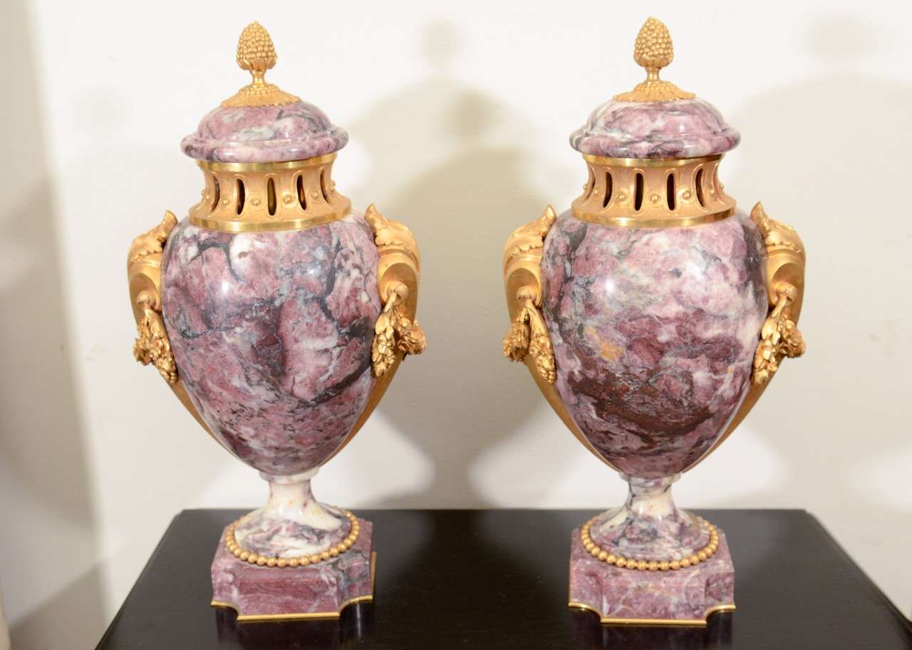 Pair of French gilt bronze-mounted rouge marble urns with acorn finials, acanthus mounts and beeding.