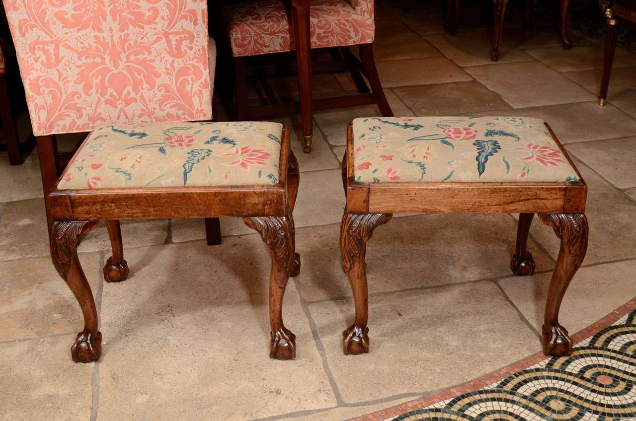 A fine pair of George II Walnut ball and claw foot stools with slip seats and carved acanthus knees.