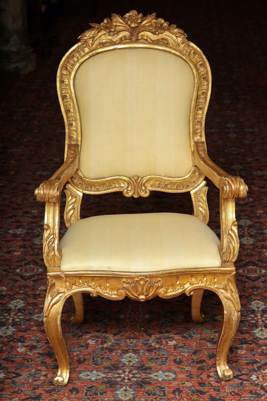 pair of rococo style 19 century  Italian gilt wood armchairs.
Each arched top rail carved with flower heads above the padded back, flanked by shaped arms ending in scrolls, the drop-in seat raised on cabriole legs
Stock Number: F14