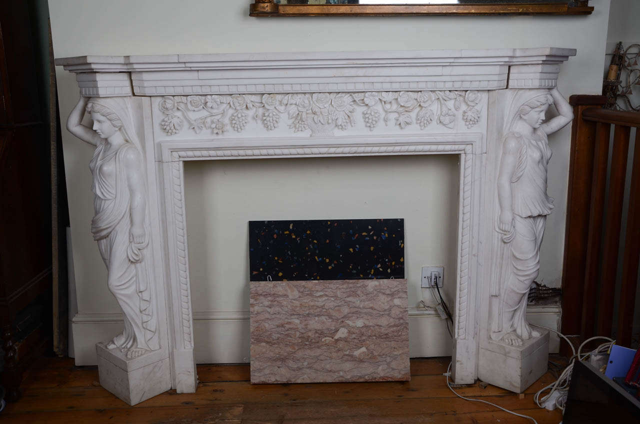 A striking and impressive statuary marble fireplace surround with ornate carved decoration. The large marble surround is in the Greek Revival style, popular from the late eighteenth century to the early nineteenth century. The break-front shelf sits