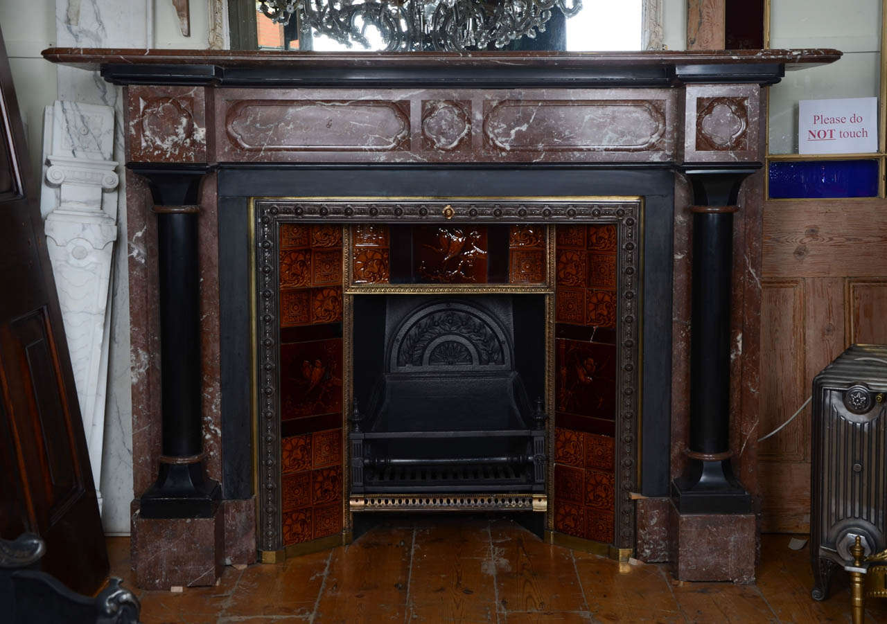 An outstanding and impressive fireplace in the Victorian Gothic Revival style. The large rouge royal marble surround features the typically Gothic quatrefoil motif and has striking black marble columns on each jamb. The fireplace includes the