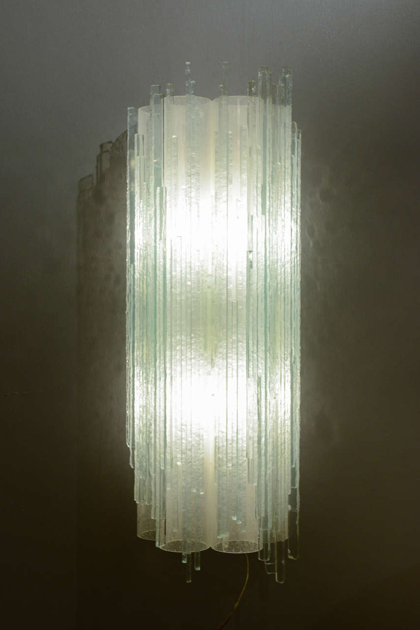 Beautiful set of three Murano glass wall sconces.
Each sconce is made of four round glass tubes covered with glass sticks which the outside sides have been carved to give this aggressive look and touch that provide a Brutalist aspect.