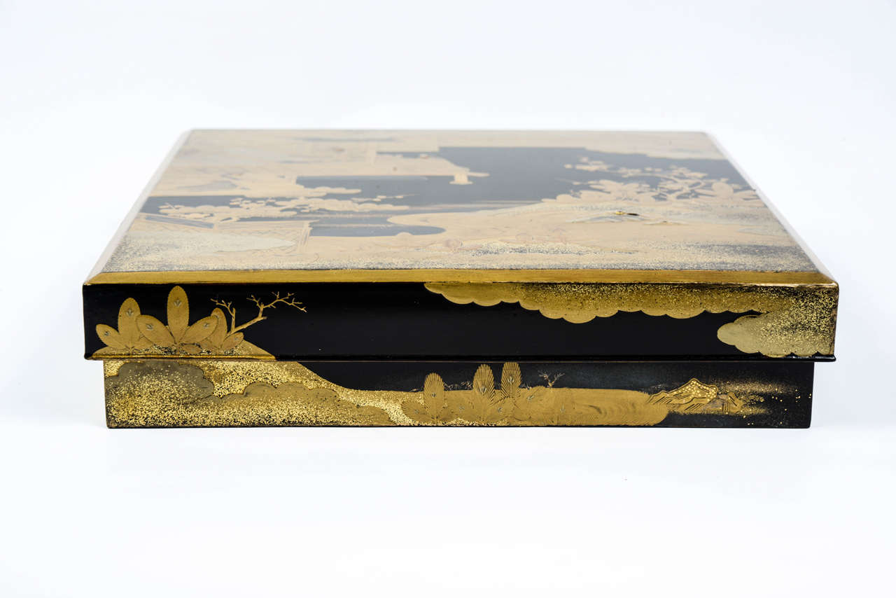 Beautiful suzuribako in black lacquer with gold decoration. The cover depicts a scene from the 'Tale of Genji' book and shows three young women in a house situated in a flowery garden. The interior contains an ink stone, a water bucket and two