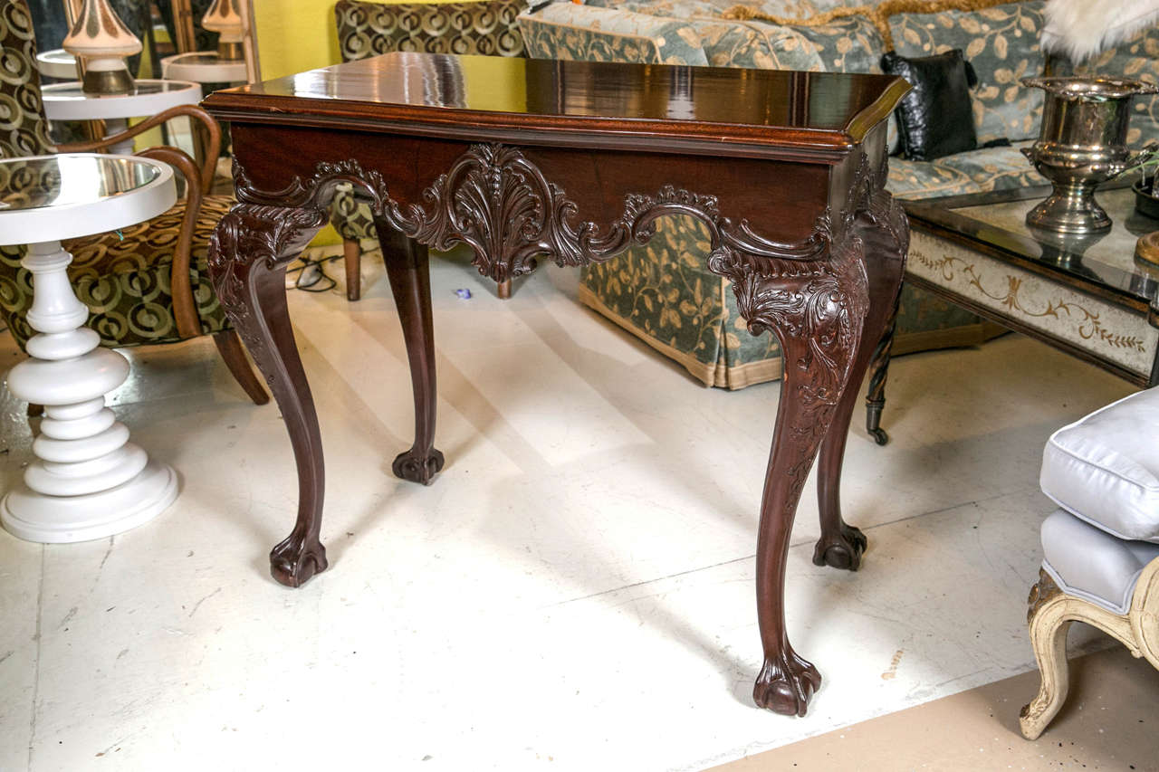 Handsome pair of English Georgian style mahogany side or console tables. Each having a molded serpentine top above a rocaille carved frieze, raised on cabriole legs headed by foliate shield ending in finely carved talon ball and claw feet. The fine