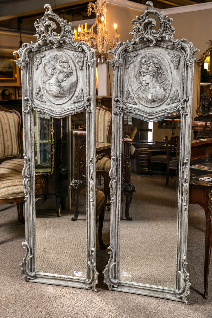 A glorious pair of Swedish style distressed pint decorated gesso mirrors. The tops forming a feminine curvature with an addition of two opposing women. The color is a beautiful whitewashed Robin's egg blue. The carved leaf and flowers atop and
